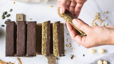 Hands picking up a Macadamia, Pumpkin Seed And Fudge Protein Bar