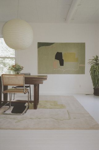 Dining room with rug in cream and green with a matching painting