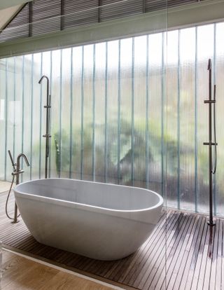 The master bathroom features a floor-to-ceiling reeded glass wall