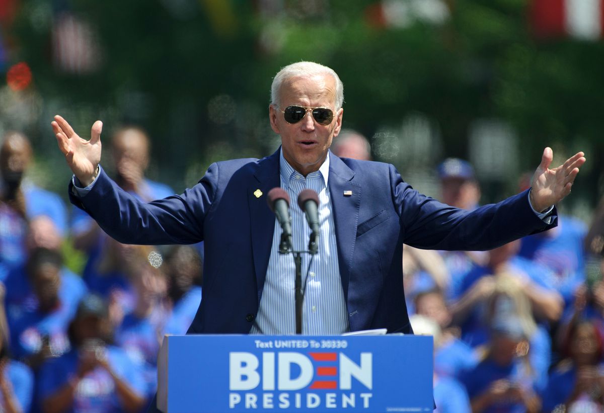 Joe Biden behind the campaign podium with his arms spread open