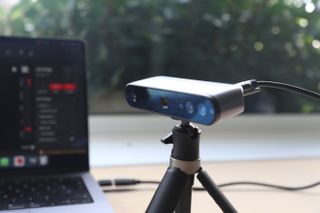 A Revopoint INSPIRE 3D Scanner on a desk, along with an object to scan and a laptop