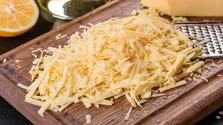 Lump of grated cheese on wooden chopping board