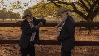 Hamilton Morris as Uncle Bryce and Robert Taylor as Colin Lawson, leaning on a horse enclosure fence, in Territory.