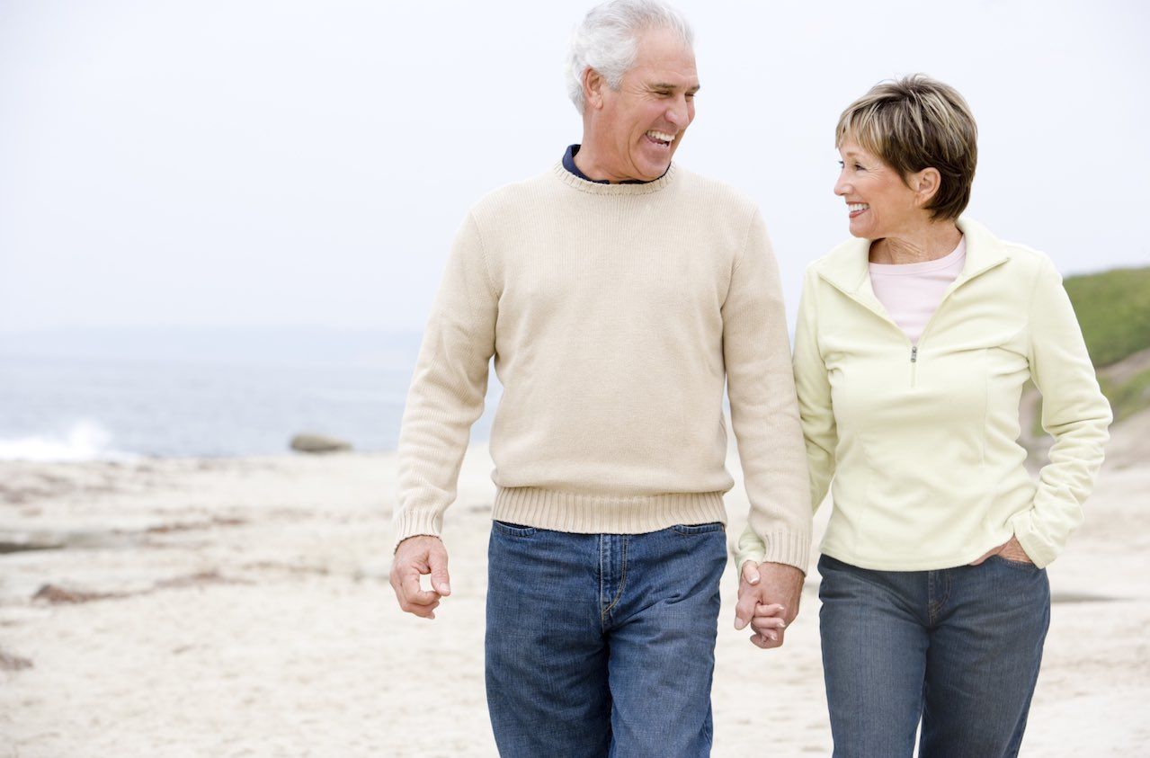 Couple at the beach holding hands and smiling