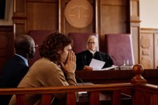 A man covers his face while in front of a judge in probate court.