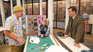 Tony with Esme and Patrick around a sewing bench in The Great British Sewing Bee series 9