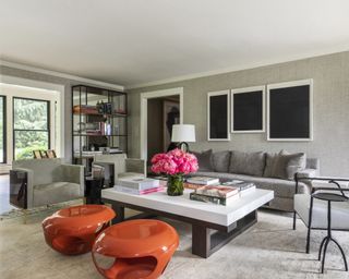 A living room with grey wallpapered walls, grey sofa, and orange stools
