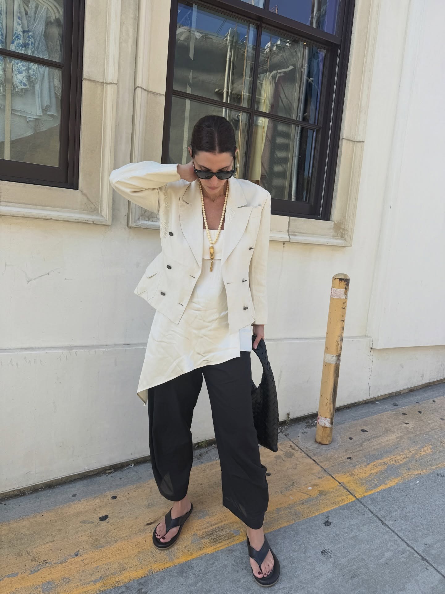 Woman in blazer, top, pants, and long necklace.