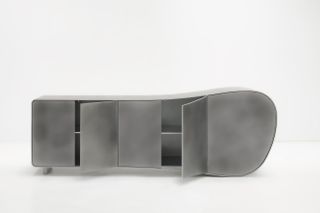A silver cabinet sinuously shaped like a stylized whale with simple doors on the front