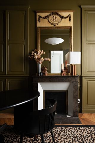 olive green townhouse interior with black stone fireplace and cheetah print rug