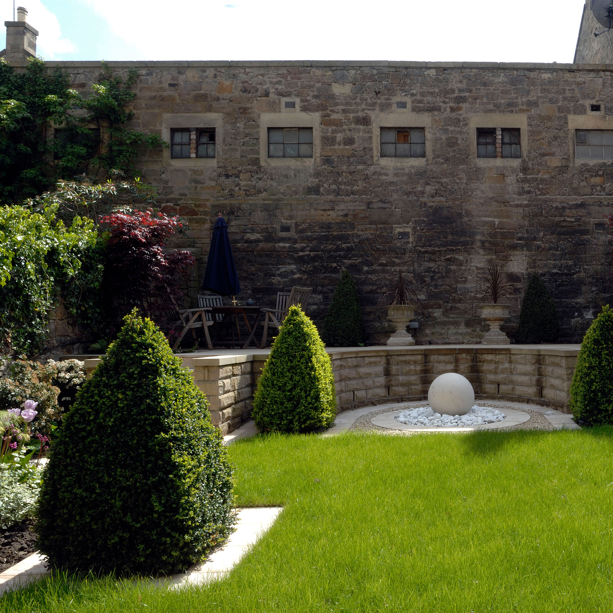 exterior of stone building with lawn and topiary