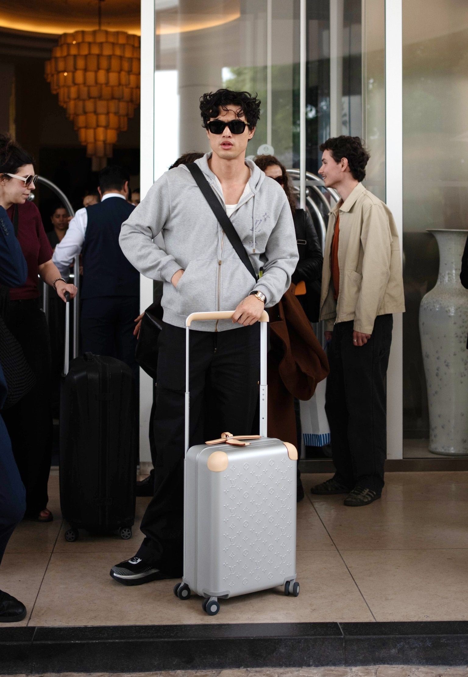 Charles Melton with a Louis Vuitton suitcase