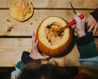 child scooping out the insides of a pumpkin