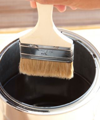 paintbrush in a tin of black paint