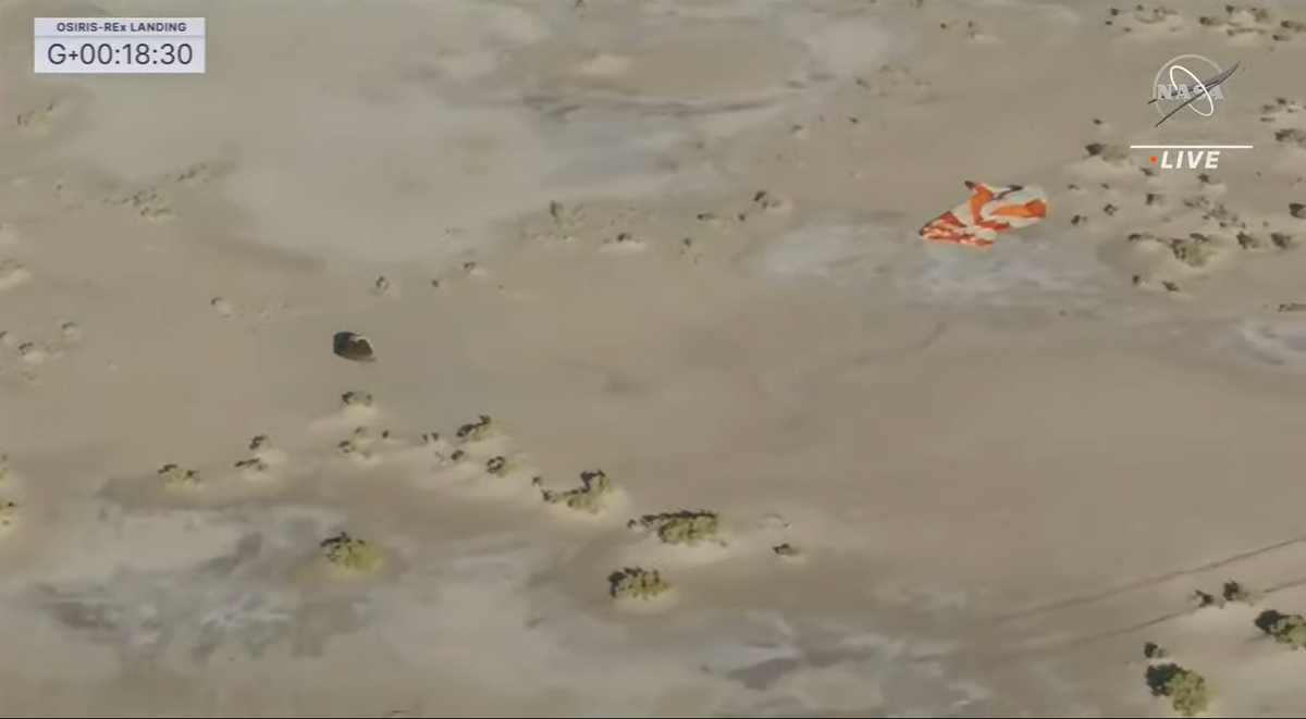 The sample capsule is seen next to the parachute on the ground.
