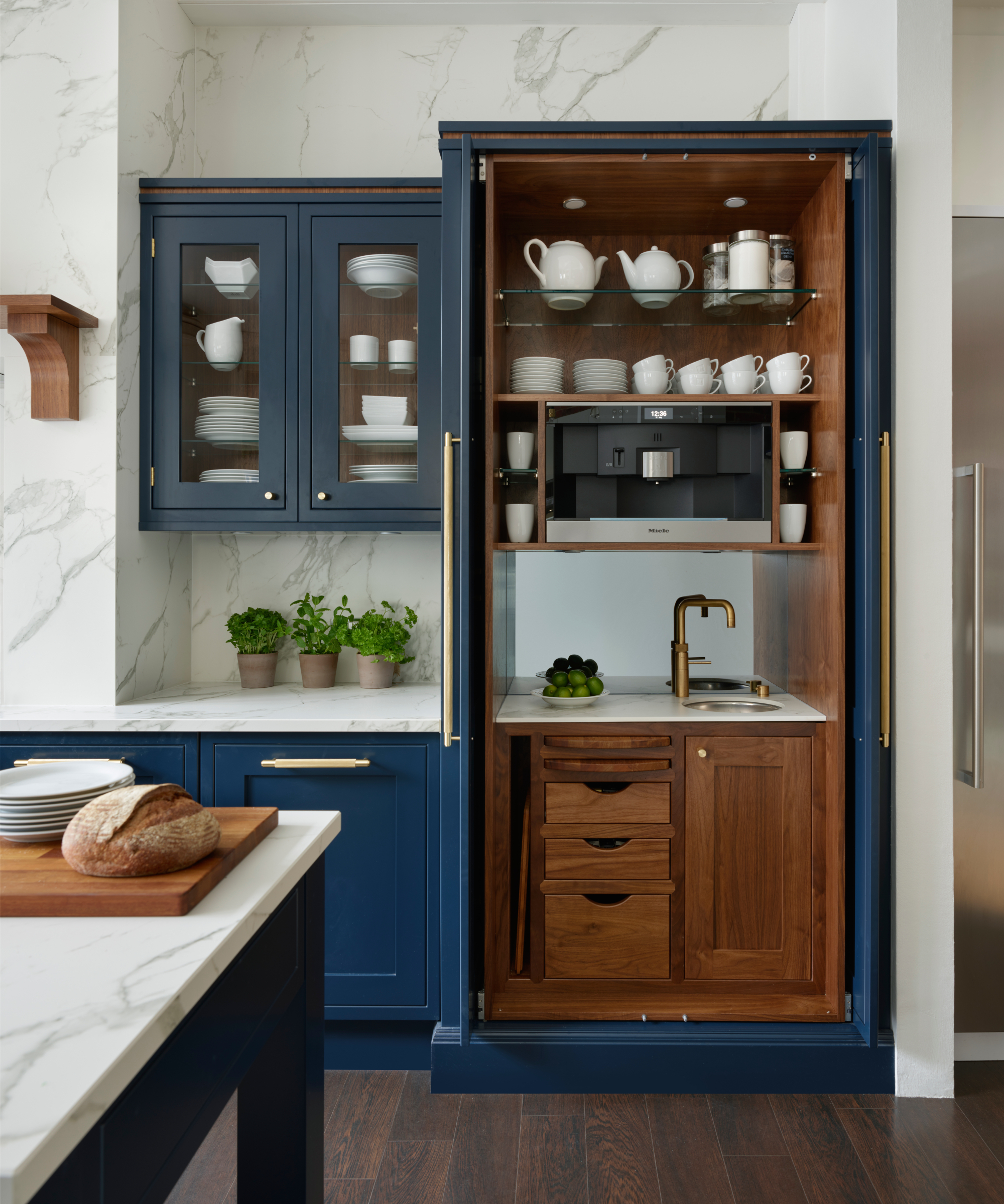 full-height kitchen cabinet with doors open to show worktop with sink, prep area, coffee machine above and crockery on shelves