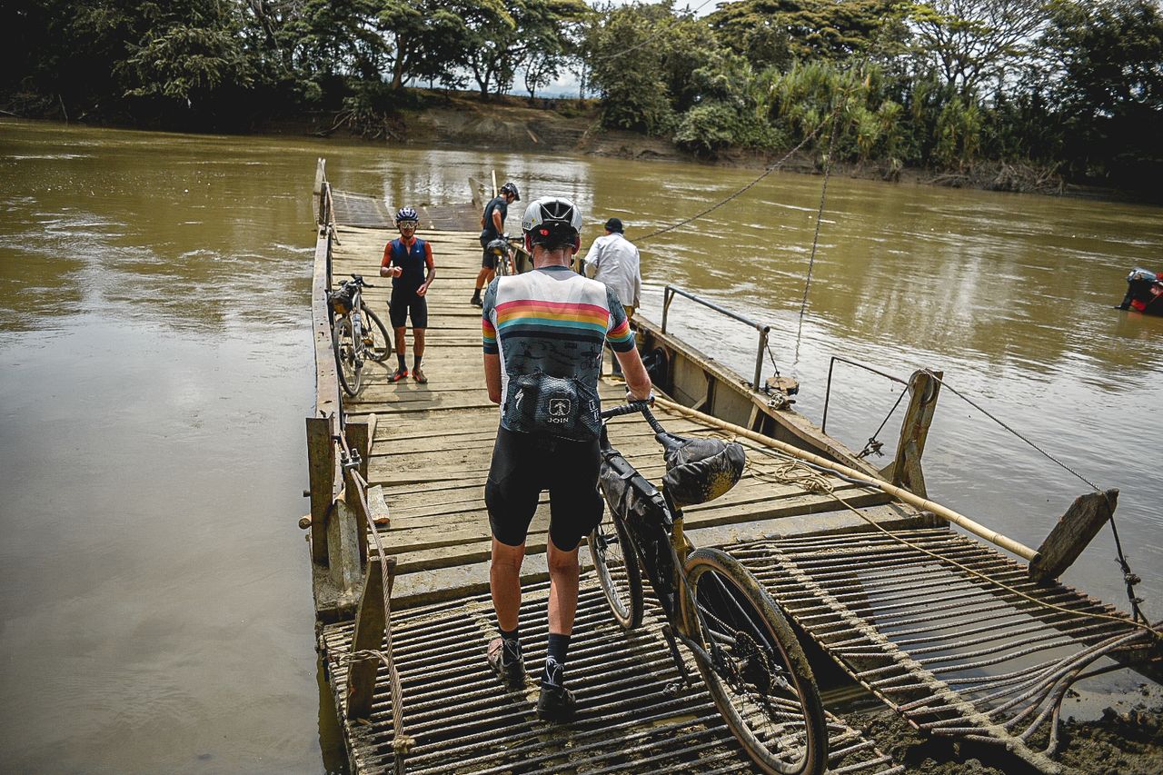 Laurens ten Dam walks his bike onto local ferry to cross Cauca River on stage 2