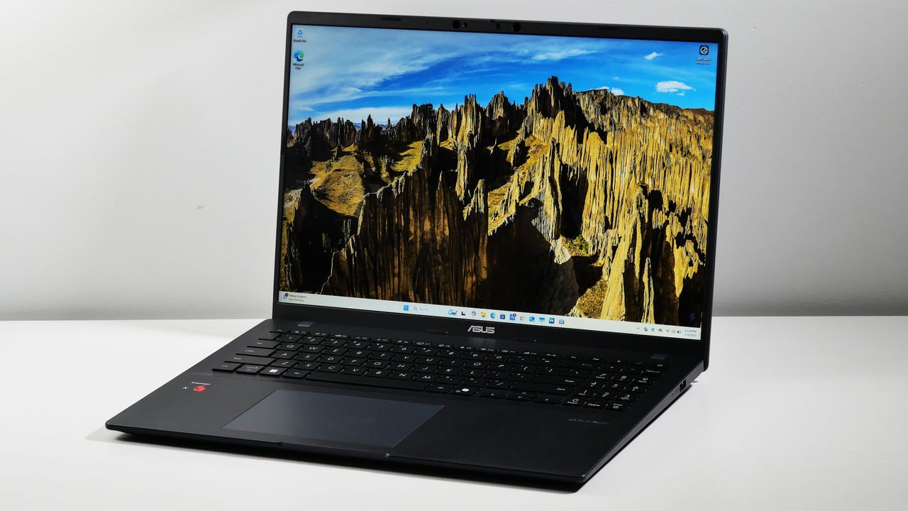 Angled view of the Asus Vivobook 16 (2025) open and powered on in front of a light gray background.