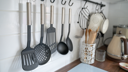 Black plastic kitchen utensils hanging in kitchen