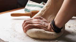 Hands kneading dough on a counter top
