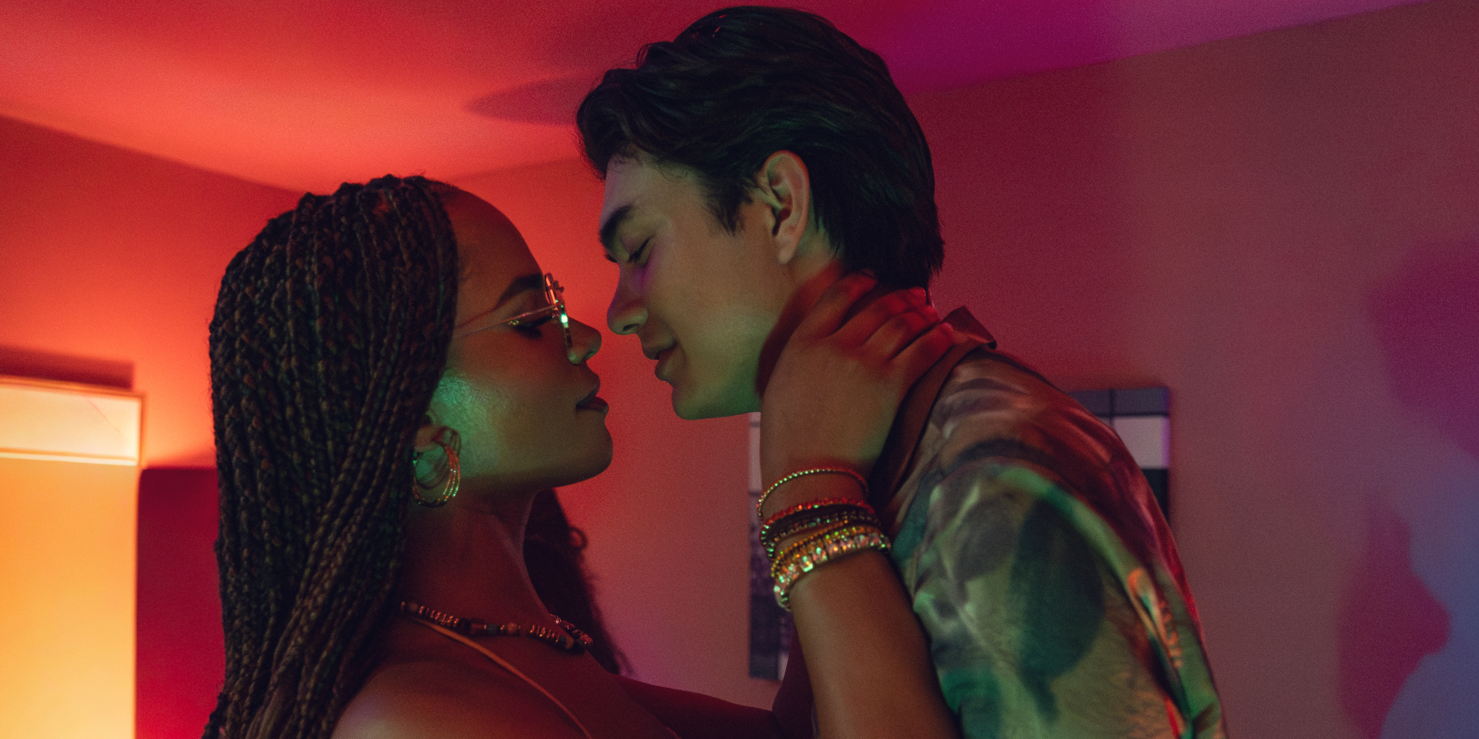 Yasmin Finney and Will Gao lean in for a kit in an orange lit room in the movie heartstopper forever