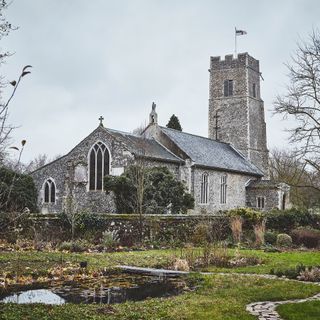 view of church and garden in winter with winding path and pond