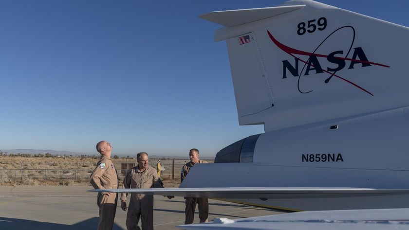 a white jet with an elongated nose section sits on a tarmac at sunset