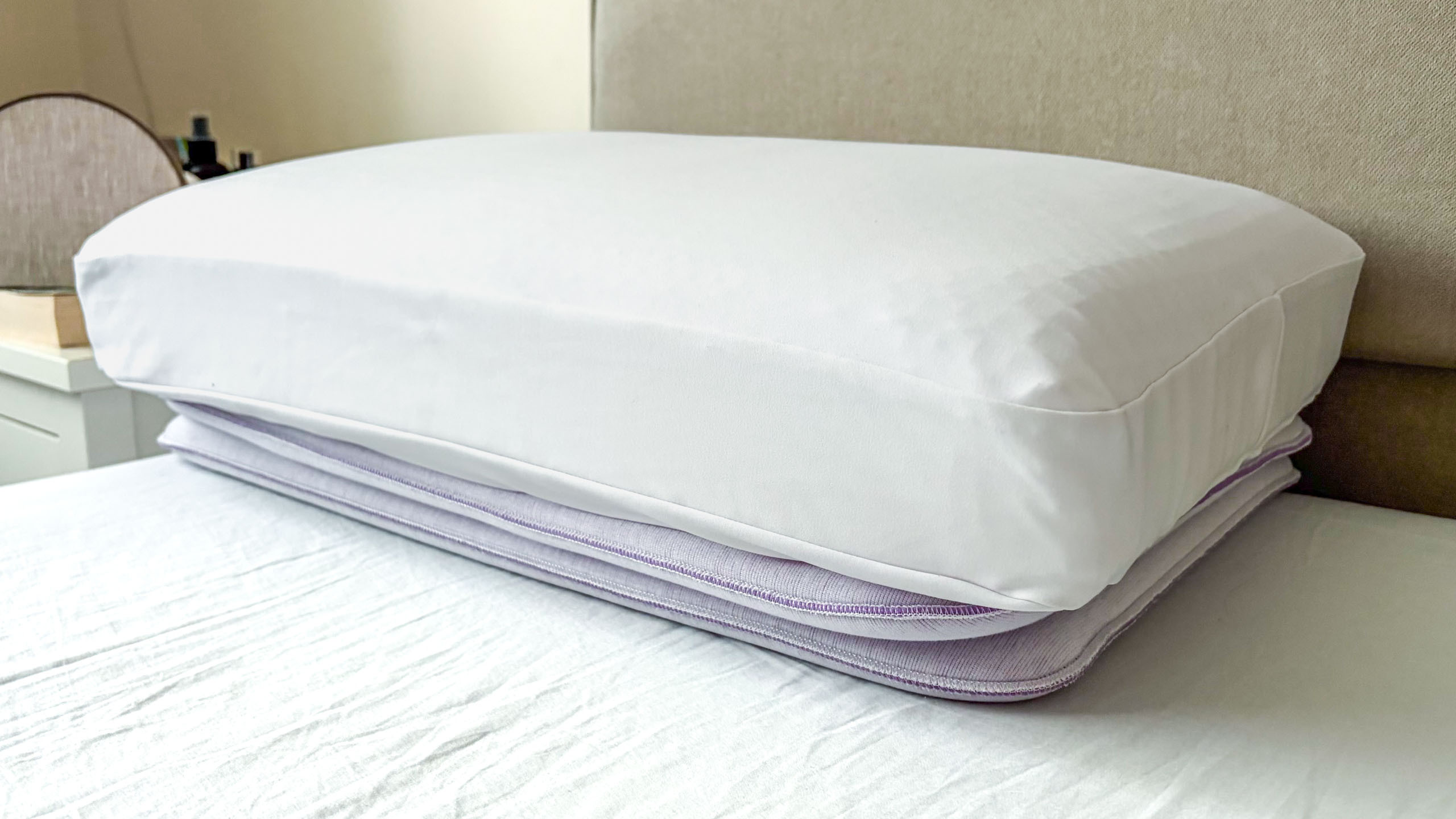 A close up of the Purple DreamLayer Pillow resting on its booster layers, on the bed in our reviewer's bedroom