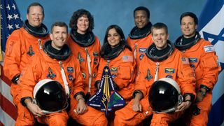 seven astronauts in flight suits posing for a portrait