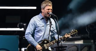 Noel Gallagher plays a Gibson Les Paul and sings into the mic as he performs with Oasis at their long-awaited reunion shows.