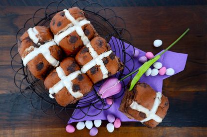 Mini Egg chocolate hot cross buns in a wire basket with a purple tulip and mini eggs scattered