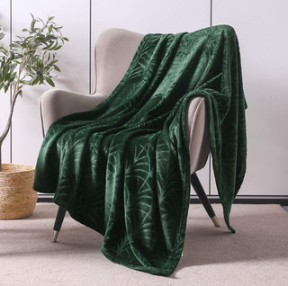 Green fleece throw draped over an armchair beside an olive tree.