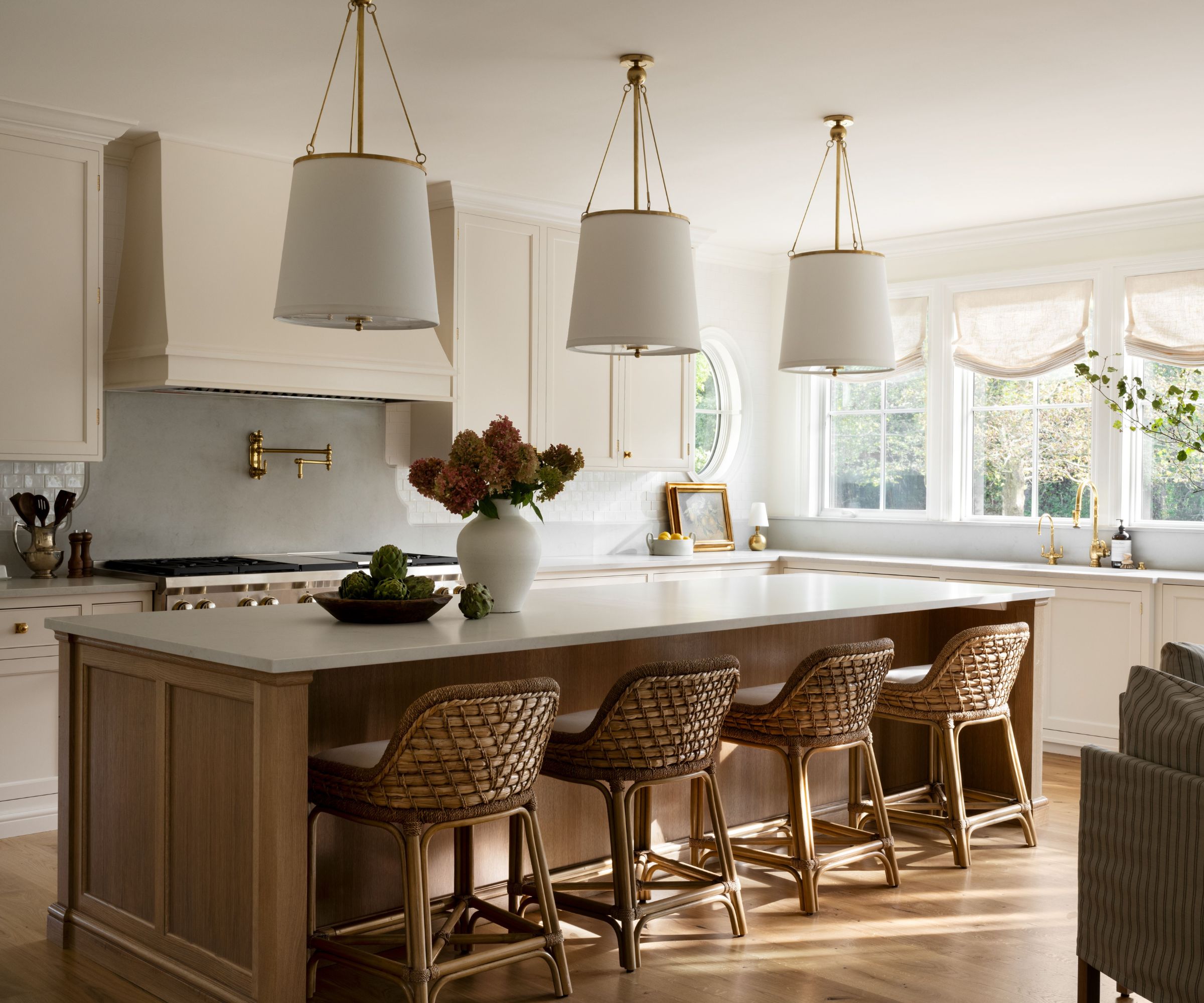 A warm neutral kitchen with off-white cabinets, a wooden island, and sheer drapes over the windows