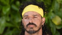 Ozzy thinking on Survivor 50 with a yellow headband. 