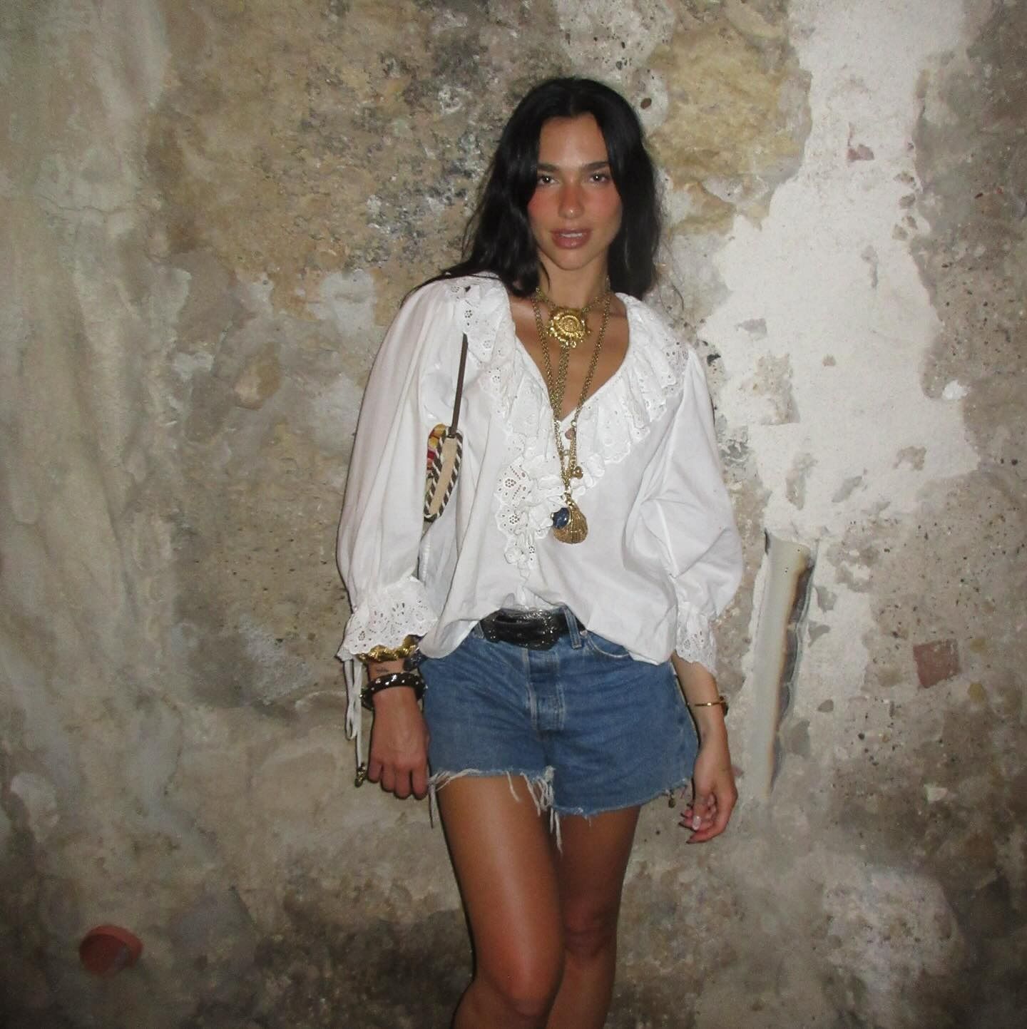 Dua Lipa wearing a pretty white shirt and denim shorts on vacation in Palermo, Italy