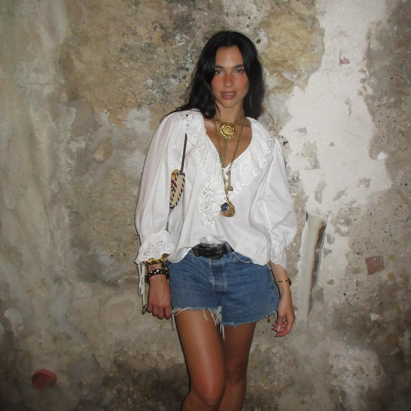 Dua Lipa wearing a pretty white shirt and denim shorts on vacation in Palermo, Italy