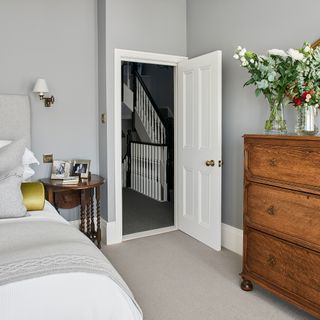 Grey bedroom with bed, neutral carpet and wooden furniture