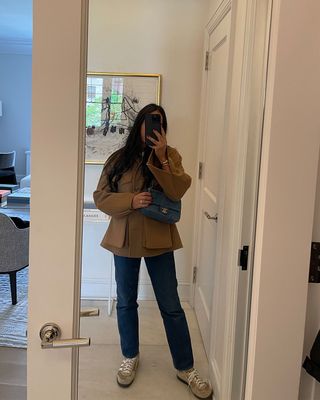 A woman taking a mirror selfie and holding a Chanel Flap bag.