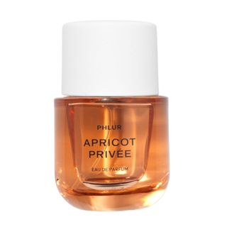 A press shot of an orange glass bottle of Phlur Apricot Privée EDP