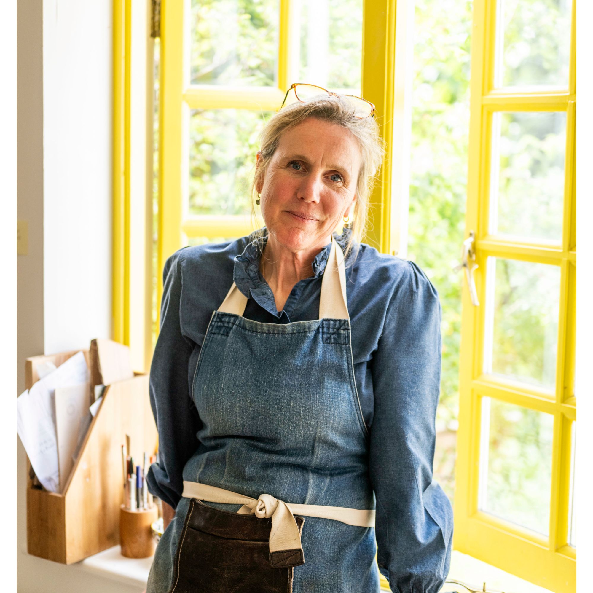 blonde woman in denim apron smiling at camera