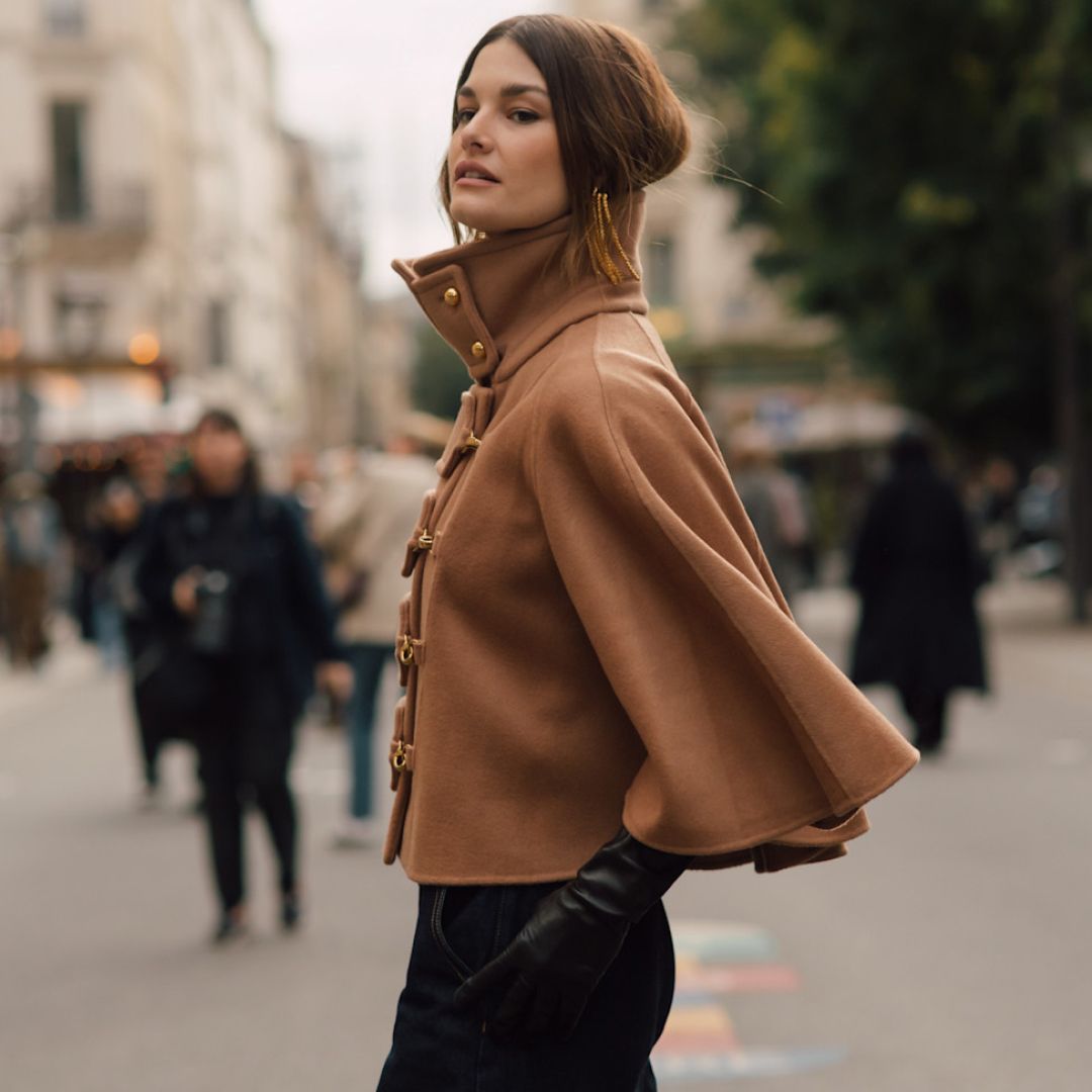 fashion week attendee wearing beige cape and leather gloves