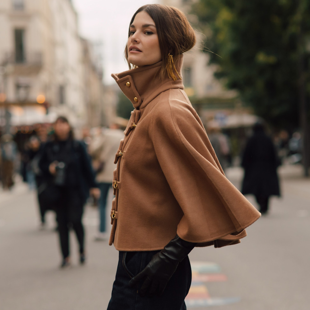 fashion week attendee wearing beige cape and leather gloves