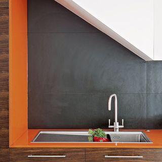 kitchen area with matt-black tiled wall and orange worktop with sink