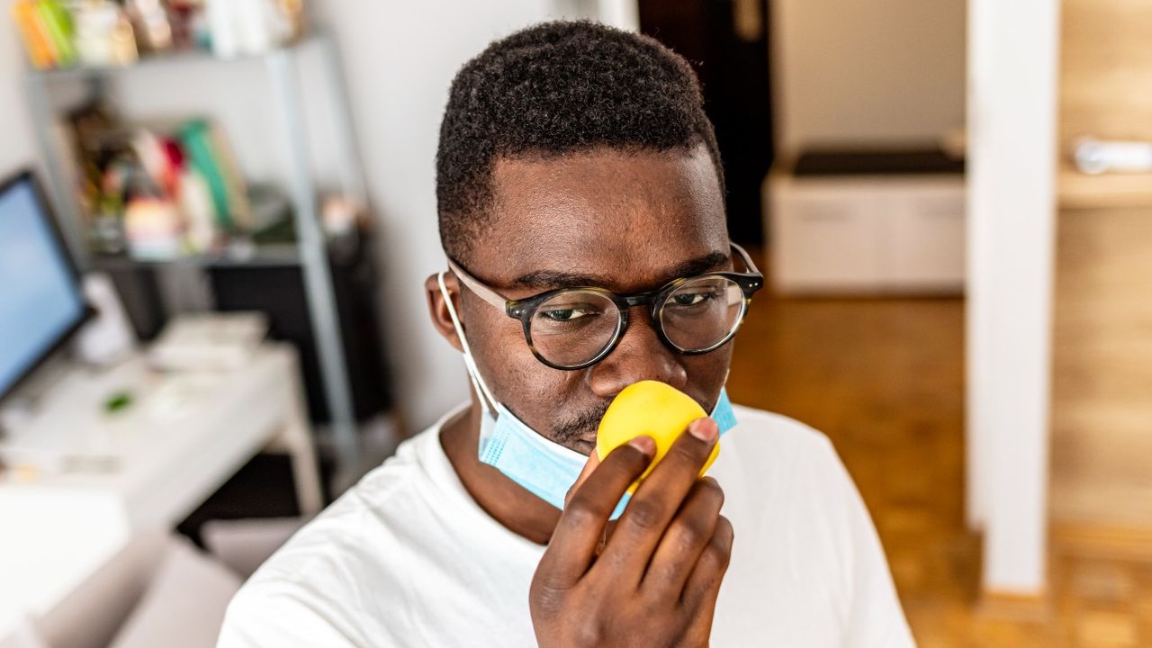 man sniffing orange to restore sense of smell