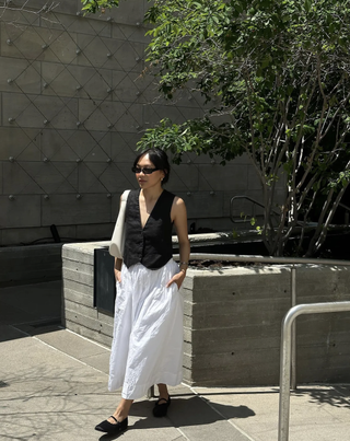 woman wearing satin ballet flats and white skirt