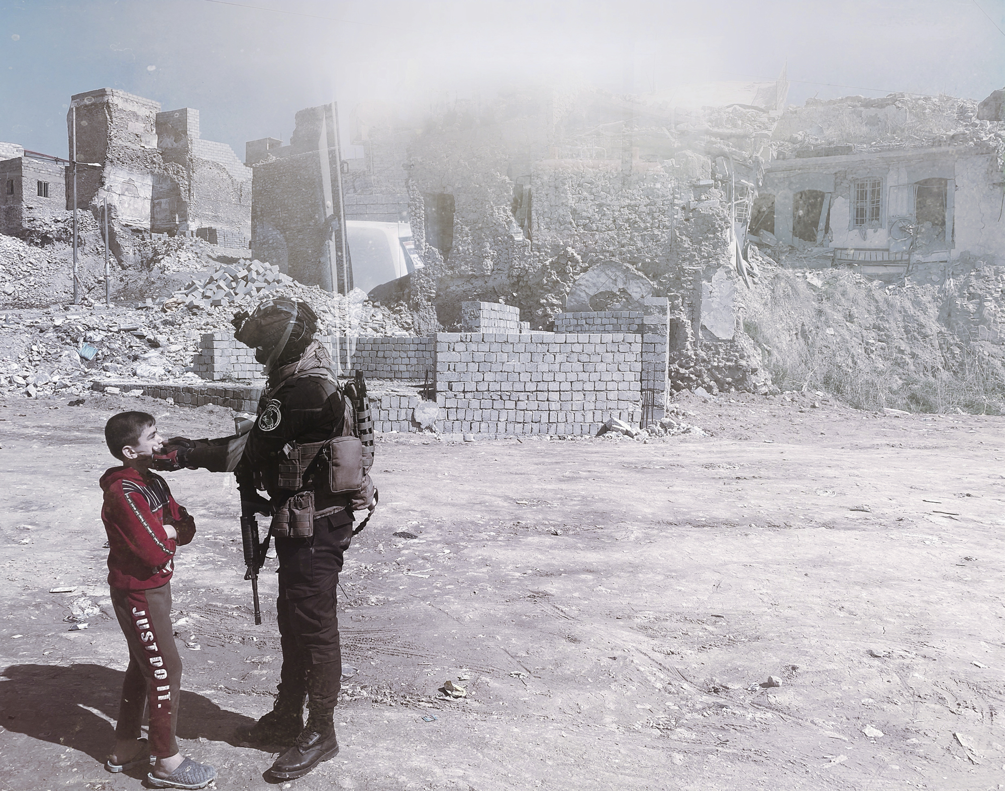 A soldier talking to a little boy in front of the ruins