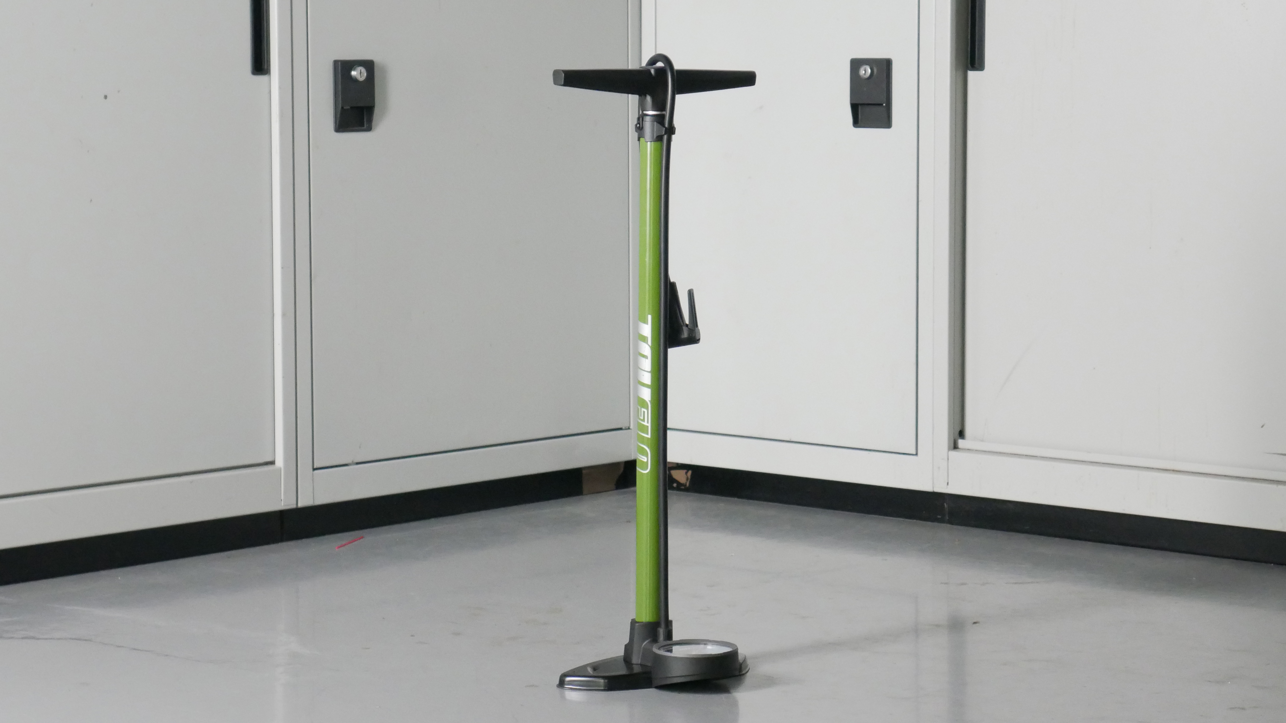 Truflo bike track pump in green set to a background of some workshop cabinets