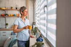 Woman Looking Out The Window And Drinking Coffee