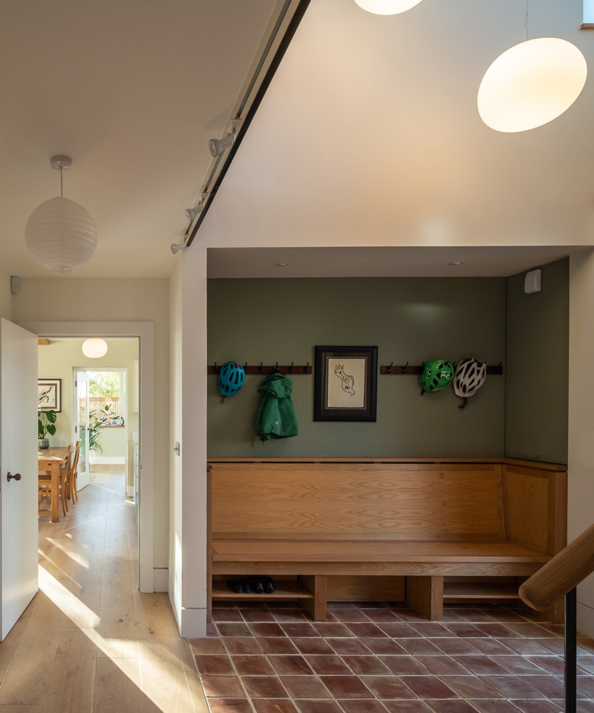 A hallway with a built in seating and hooks for coats