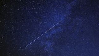 A meteor is pictured shooting diagonally through a starry night sky.